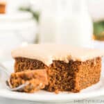 a slice of gingerbread cake with caramel icing with a forkful of cake beside it