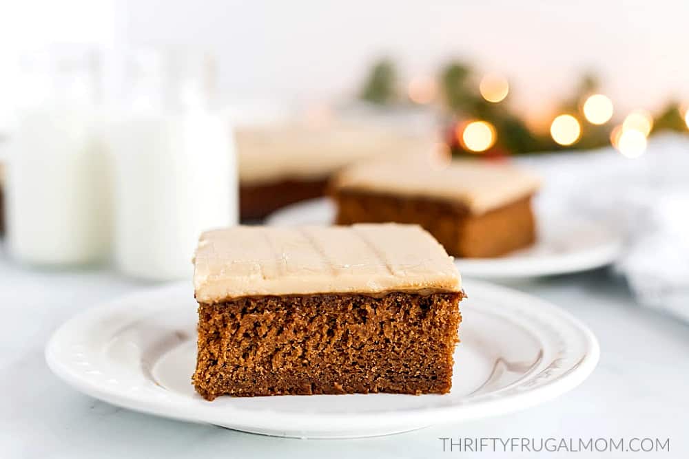 a square of gingerbread cake topped with frosting on a white plate