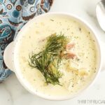 a white bowl full of cream cheese potato soup with ham and dill
