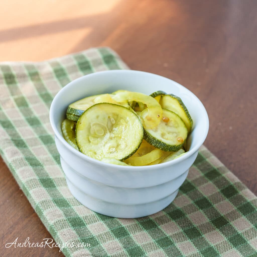 zucchini pickles in a white bowl on a green checkered napkin