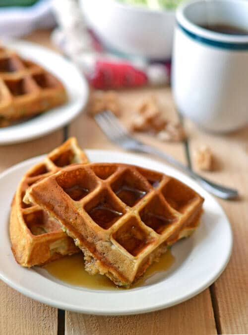 two zucchini waffles with syrup on a white plate