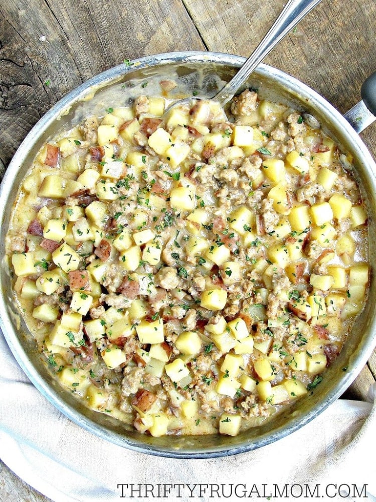 Creamy sausage and potatoes in a skillet on a wooden table