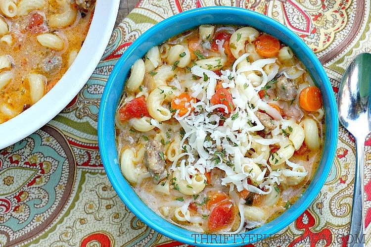 Creamy Italian sausage and pasta soup in an aqua bowl on a paisley tablecloth