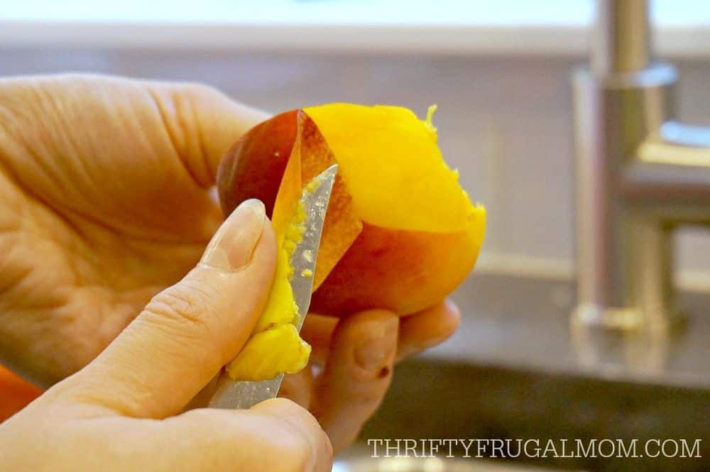 a peach slice being held and peeled