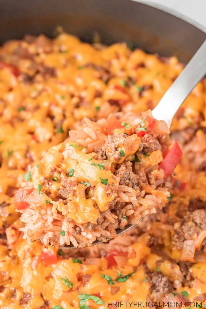 Spanish rice with ground beef being spooned out of a pan