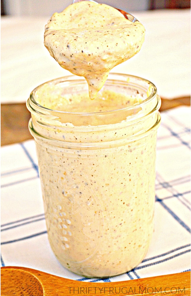 homemade Alfredo sauce being spooned out of a glass jar
