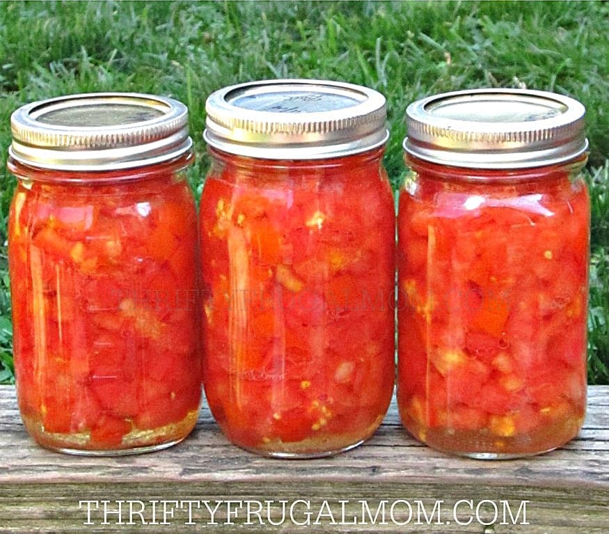 3 jars of home canned diced tomatoes sitting on a wooden table