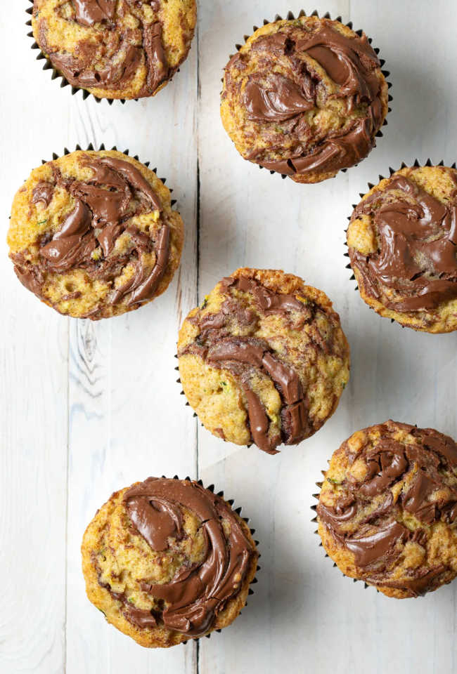 Zucchini muffins with nutella swirls arranged on a white tabletop