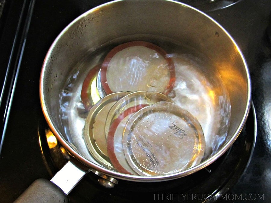 canning jar lids in boiling water in pan on stove