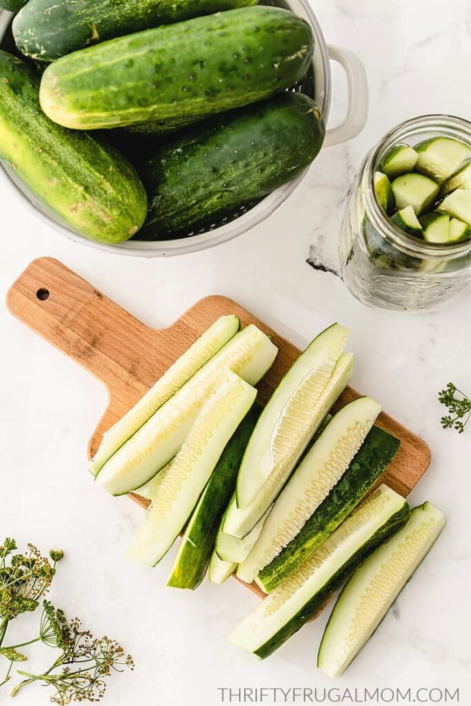 Cucumbers slices on a wooden cutting board for homemade dill pickles