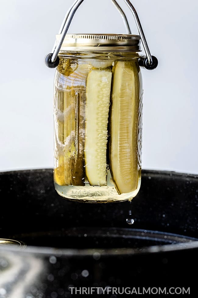 jar of homemade canned dill pickles being taken out of canner