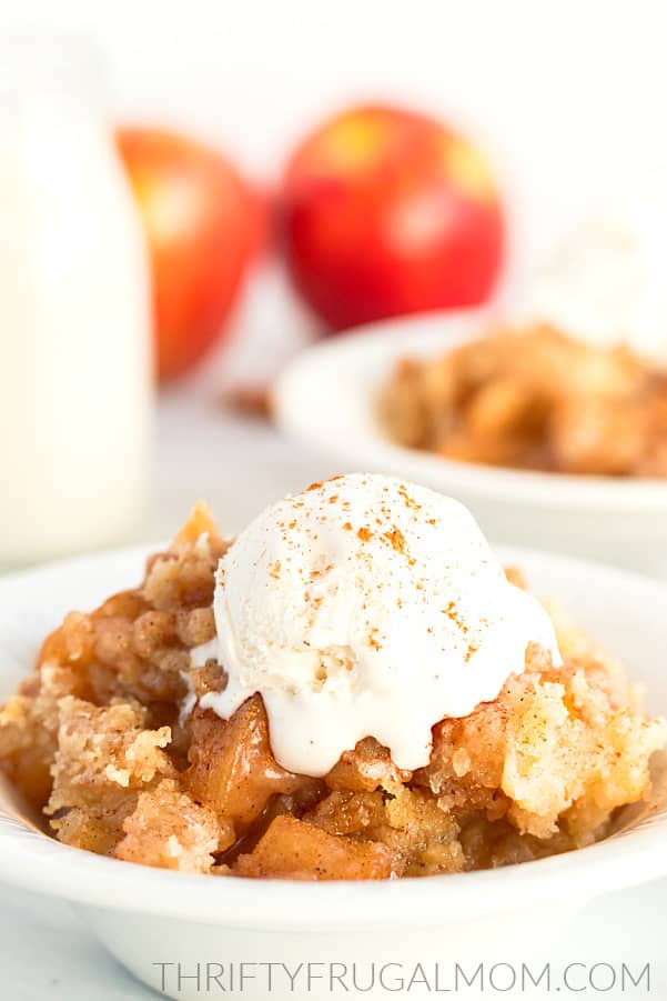 a white bowl full of from scratch apple dumpling dessert topped with a scoop of vanilla ice cream