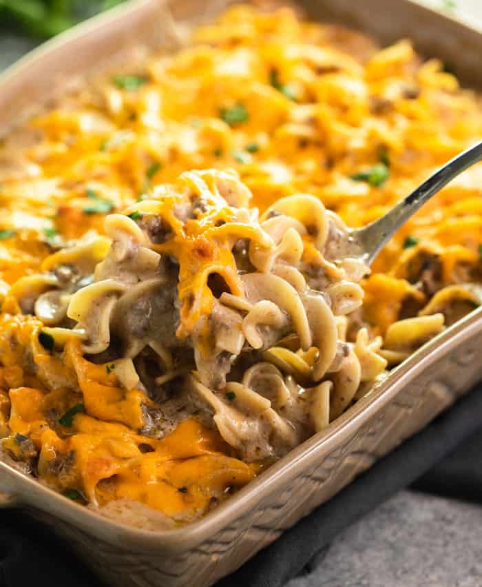 Easy, kid-friendly Ground Beef Stroganoff Casserole being spooned out of a tan baking dish.