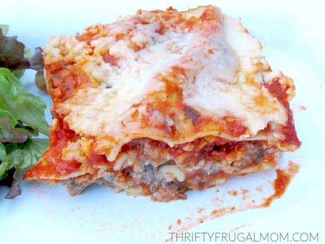 a slice of frugal Oven Ready Lasagna on a white plate with some lettuce