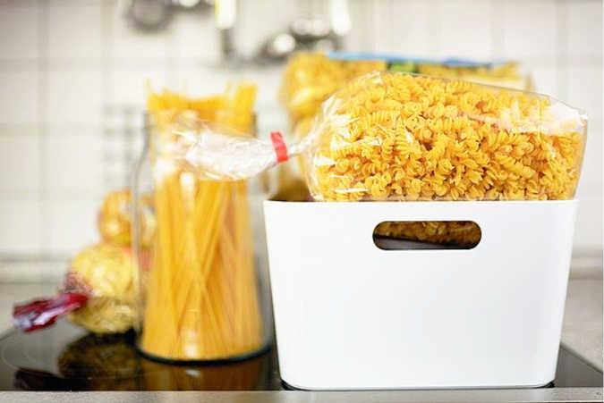 a plastic box full of a bag of dried pasta sitting beside a jar of dried pasta- substitute