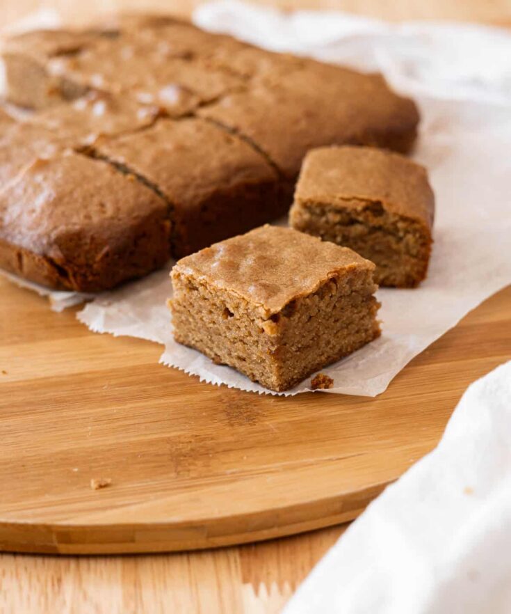 No Butter Blondie Brownies arranged on a wooden cutting board with parchment paper underneath them.
