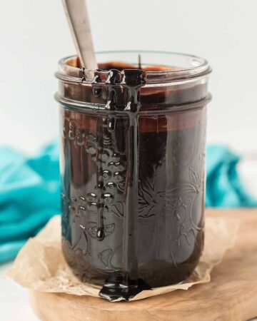 homemade chocolate syrup in a small mason jar with a spoon stuck in