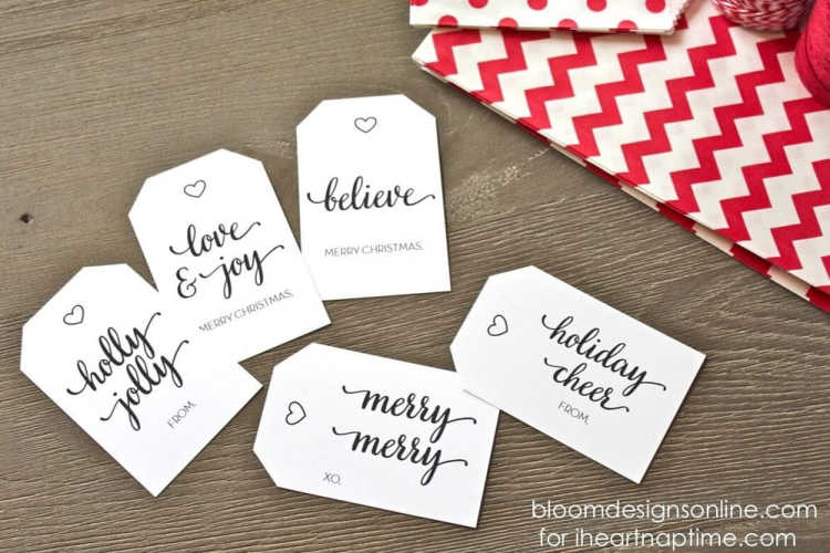 5 black and white simple free printable Christmas gift tags on a wooden table