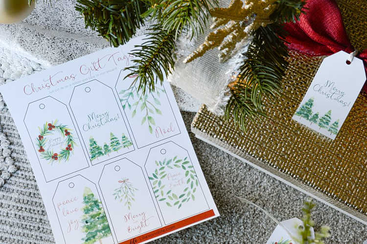 a sheet of printable watercolor Christmas tags on the floor with a Christmas tree and gift