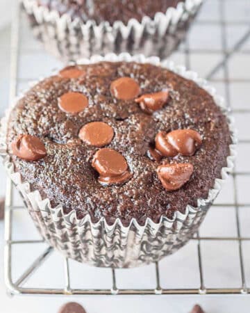 close up of a double chocolate muffin on a wire rack in a muffin cup liner
