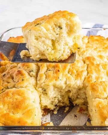 a dish of garlic butter swim biscuits with one sitting on top