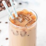 close up of a homemade iced vanilla latte in a glass with 2 straws