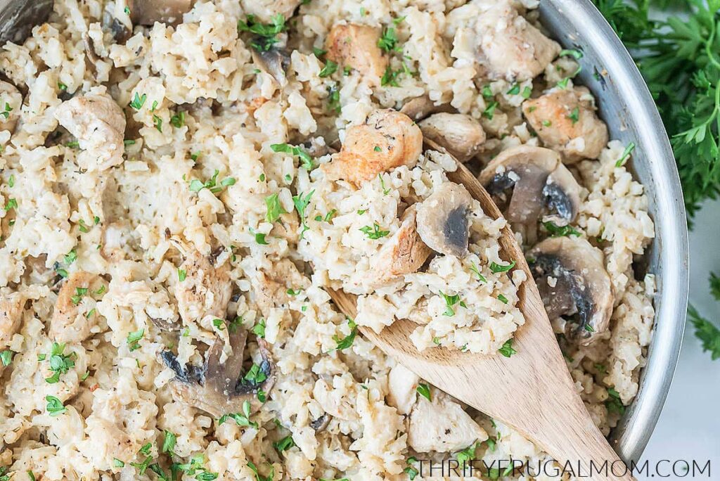 creamy chicken, rice, and mushrooms in a pan with a scoop on a spoon