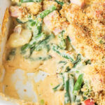 top view of ham and potato casserole with green beans with a serving missing