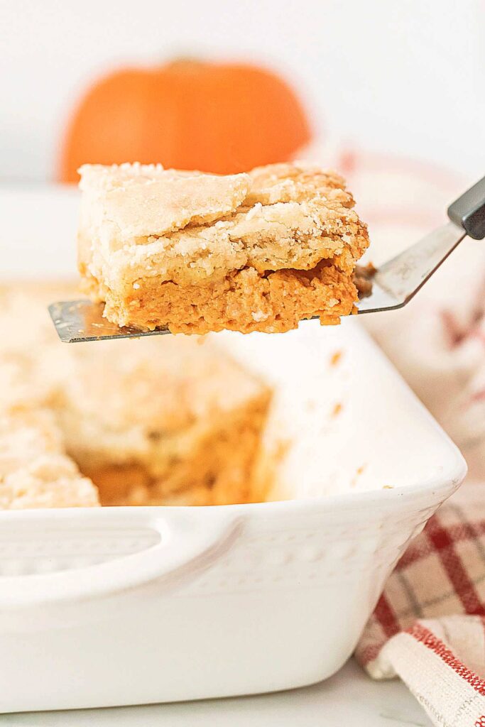scooping a slice of pumpkin dump cake out of the baking dish