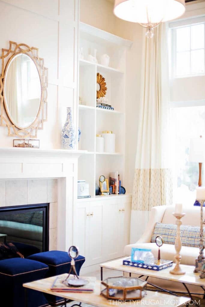 a beautiful white room with a large gold oval mirror