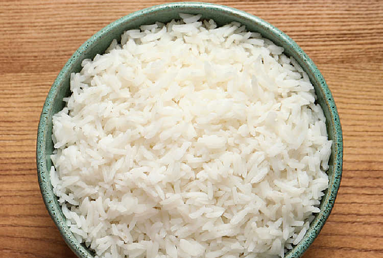 a bowl full of cooked white rice on a wooden table
