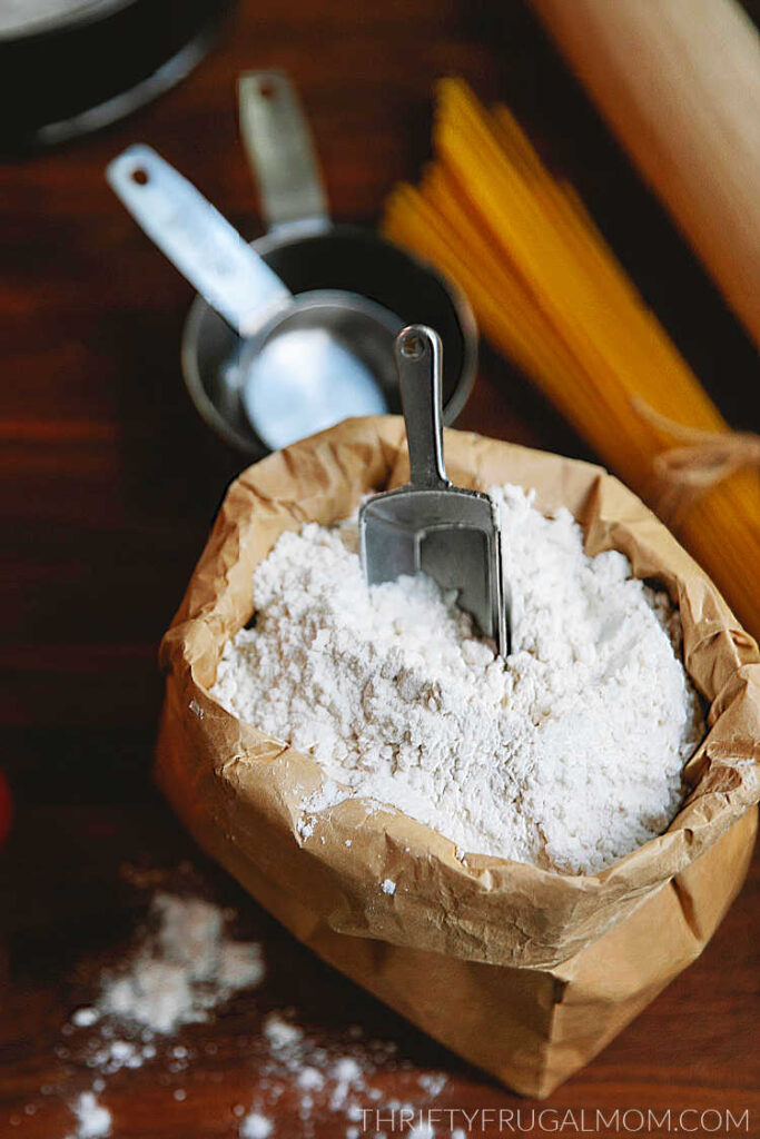 a paper bag full of flour with a scoop and other baking supplies in the background