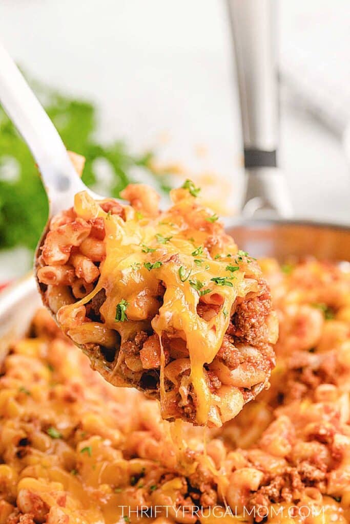 cheesy beef macaroni skillet being spooned from a pan