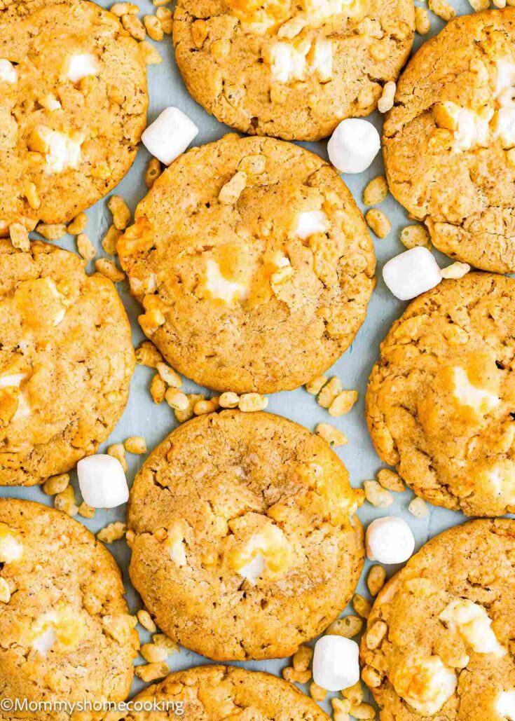 Marshmallow Rice Crispy Cookies arranged on a white backdrop with marshmallows and Rice Crispies scattered around.