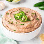 a bowl of homemade refried beans topped with 3 jalapeno slices.