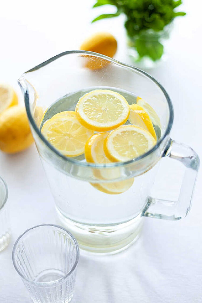 a glass jug of water with some sliced lemons