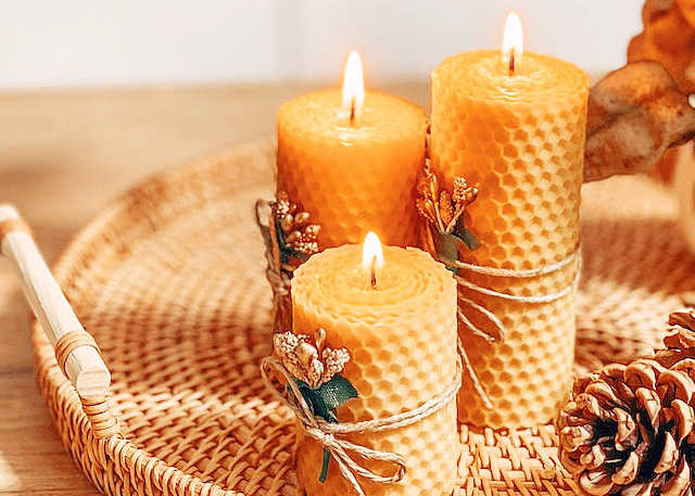 a natural wood tray with 3 beeswax candles on it