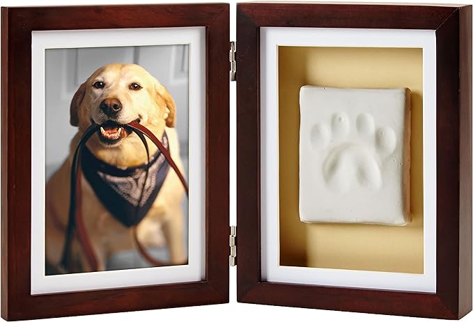 A double sided picture frame with a dog on one side and a clay paw mold on the other. 