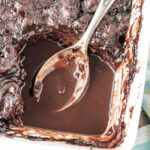 A spoon sitting in the hot fudge sauce of the chocolate cobbler.